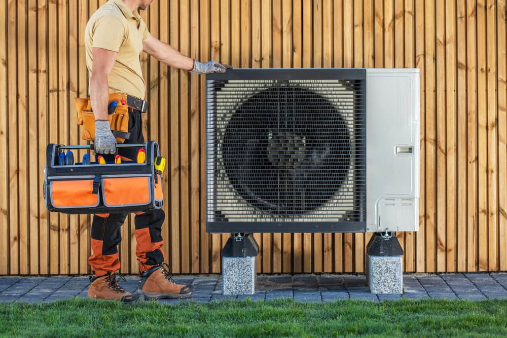 HVAC Technician Standing Next to Air Conditioning Unit